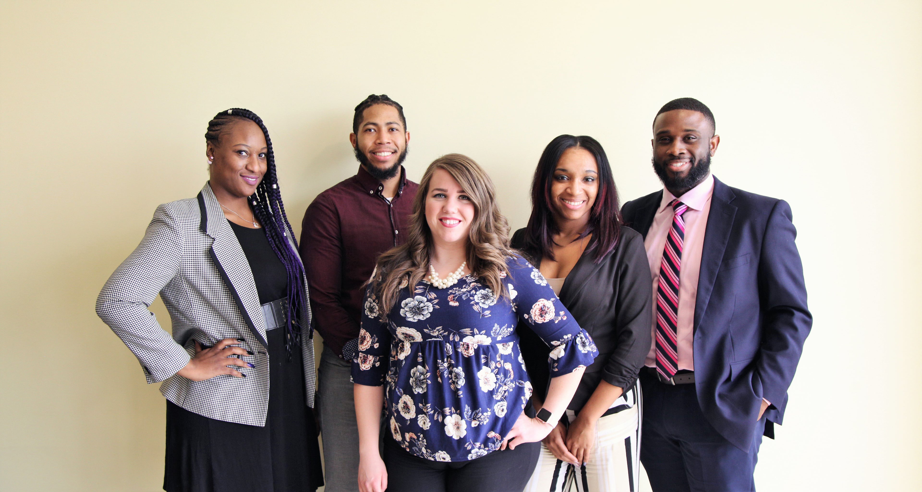Five smiling adults posing for a group photo.